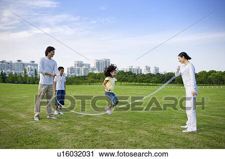 Young family with two children jumping rope on the lawn View Large Photo Image Stock Image - Young family with two children jumping rope on the lawn. Fotosearch