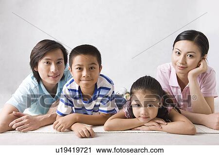 Stock Image - Young family with two children lieing on front and looking at the camera. Fotosearch