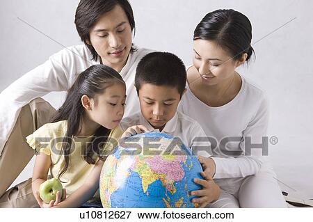Stock Photo - Young family with two children looking at the globe. Fotosearch