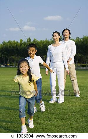 Young family with two children standing on the lawn happily View Large Photo Image Picture - Young family with two children standing on the lawn happily. Fotosearch