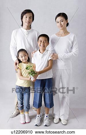 Young family with two children standing together and holding a potted plant View Large Photo Image Stock Image - Young family with two children standing together and holding a potted plant. Fotosearch