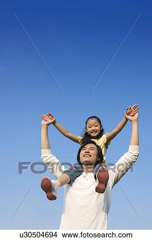 Picture - Young father carrying daughter on shoulders. Fotosearch