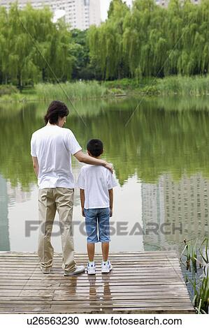Stock Image - Young father standing near the lakeside together. Fotosearch