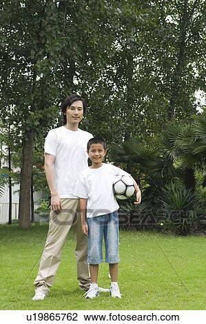 Young father standing with his son on the lawn with the football View Large Photo Image Stock Image - Young father standing with his son on the lawn with the football. Fotosearch