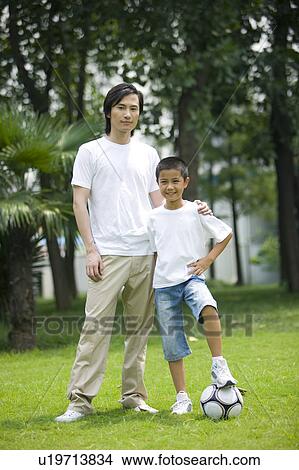 Young father with his son standing on the lawn with the football View Large Photo Image Picture - Young father with his son standing on the lawn with the football. Fotosearch