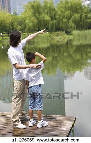 Young father with son standing by lake View Large Photo Image Stock Photo - Young father with son standing by lake. Fotosearch