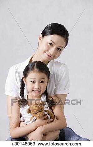 Young mother embracing her daughter, looking at the camera together View Large Photo Image Stock Image - Young mother embracing her daughter, looking at the camera together. Fotosearch