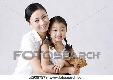Young mother holding daughter and looking at the camera together View Large Photo Image Stock Photo - Young mother holding daughter and looking at the camera together. Fotosearch