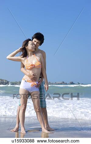Stock Photo - Young couple bonding on the beach. Fotosearch