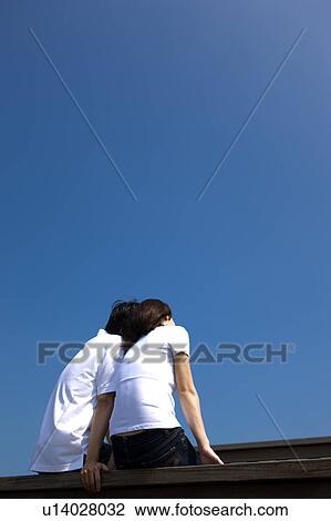 Young couple bonding together against clear sky View Large Photo Image Stock Image - Young couple bonding together against clear sky. Fotosearch