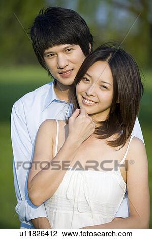 Stock Image - Young couple bonding together and looking at the camera. Fotosearch