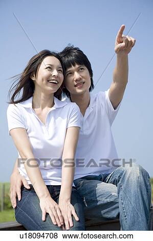 Stock Photo - Young couple bonding together and looking away. Fotosearch