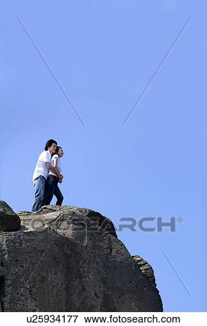 Young couple bonding together on the rock View Large Photo Image Stock Photo - Young couple bonding together on the rock. Fotosearch