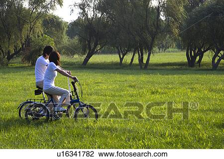 Young couple cycling on the lawn View Large Photo Image Stock Image - Young couple cycling on the lawn. Fotosearch