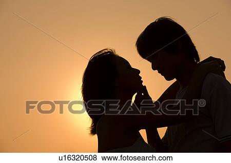 Stock Photo - Young couple embracing together and looking at each other. Fotosearch