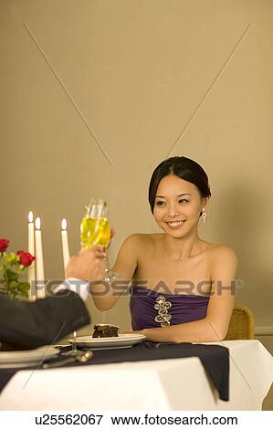 Stock Photo - Young couple holding wineglass and toast. Fotosearch