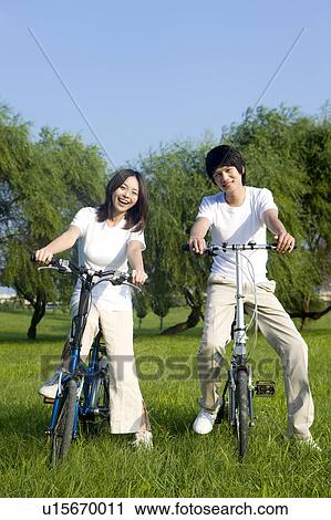 Stock Image - Young couple riding on the bicycles together. Fotosearch