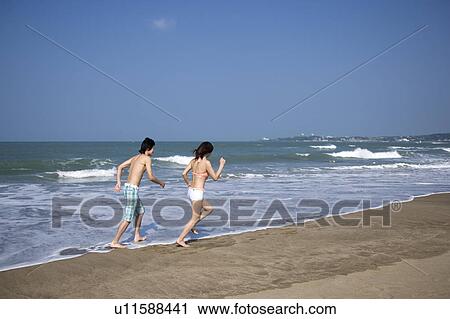 Young couple running on the beach View Large Photo Image Stock Image - Young couple running on the beach. Fotosearch