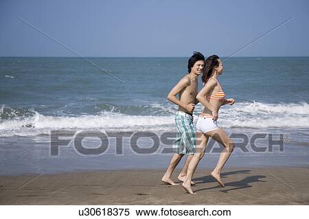Stock Photography - Young couple running on the beach. Fotosearch