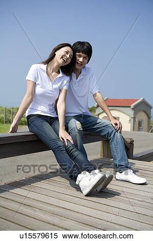 Young couple sitting on a bench View Large Photo Image Stock Photography - Young couple sitting on a bench. Fotosearch