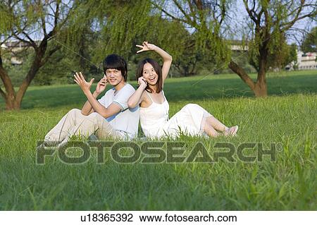 Young couple sitting on the lawn, back to back View Large Photo Image Stock Image - Young couple sitting on the lawn, back to back. Fotosearch