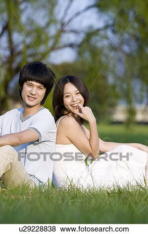 Young couple sitting on the lawn, back to back View Large Photo Image Stock Photo - Young couple sitting on the lawn, back to back. Fotosearch