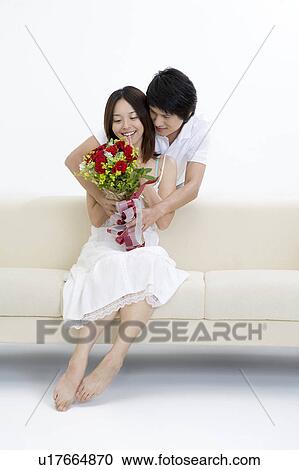 Stock Image - Young man giving a bunch of flowers to young woman. Fotosearch