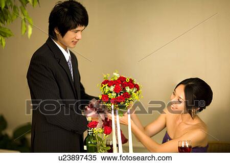 Young man giving a bunch of flowers to the young woman in candlelight dinner View Large Photo Image Stock Photography - Young man giving a bunch of flowers to the young woman in candlelight dinner. Fotosearch