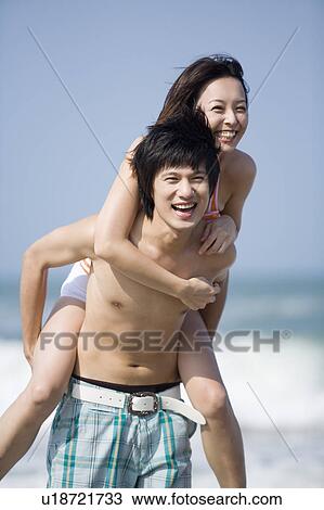 Young woman on the young man's back and smiling happily View Large Photo Image Stock Image - Young woman on the young man's back and smiling happily. Fotosearch