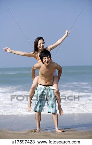 Young woman on the young man's back with arms outstretched View Large Photo Image Stock Image - Young woman on the young man's back with arms outstretched. Fotosearch