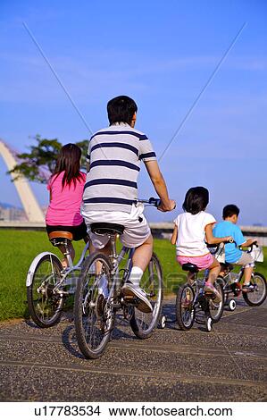 Family with two children riding on the bicycles together, rear view View Large Photo Image Picture - Family with two children riding on the bicycles together, rear view. Fotosearch