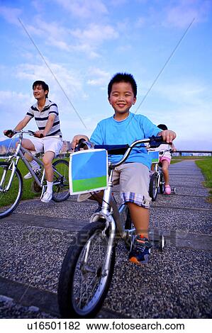 Stock Image - Father with two children riding on the bicycles together. Fotosearch