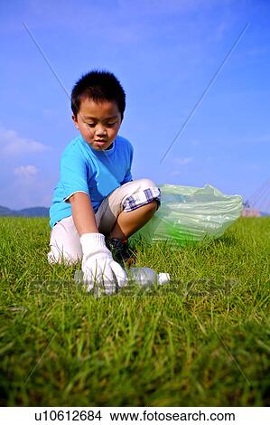 Little boy picking the empty bottle up and putting it into the garbage bag View Large Photo Image Picture - Little boy picking the empty bottle up and putting it into the garbage bag. Fotosearch