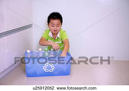 Stock Image - Little boy putting empty bottles into the recycling bin. Fotosearch