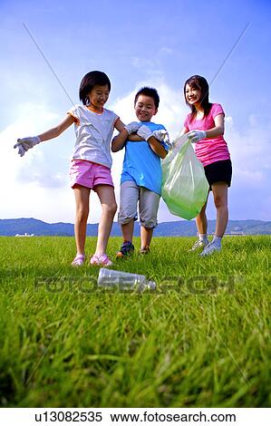 Stock Photography - Mother with two children picking the empty bottle up and smiling happily. Fotosearch