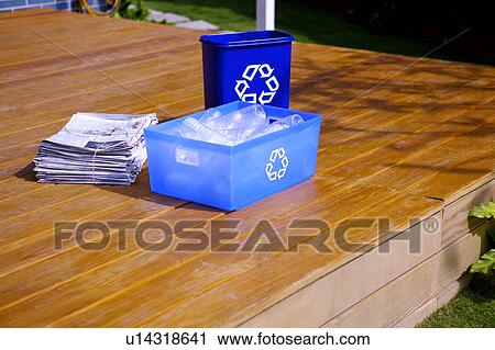 Stock Image - Recycling bins and a stack of newspaper on the hardwood floor. Fotosearch