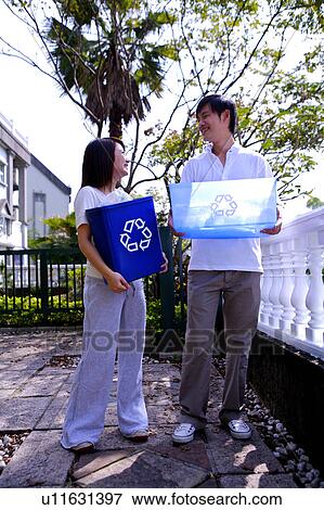 Young couple holding the recycling bins and looking at each other View Large Photo Image Stock Photo - Young couple holding the recycling bins and looking at each other. Fotosearch
