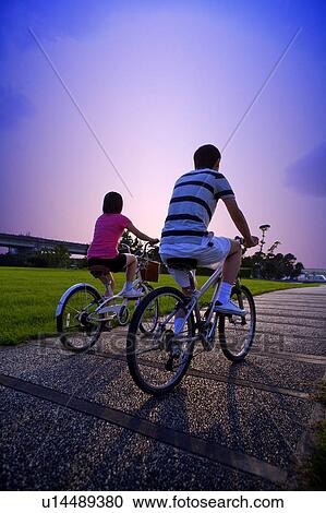 Young couple riding on the bicycles, rear view View Large Photo Image Stock Image - Young couple riding on the bicycles, rear view. Fotosearch