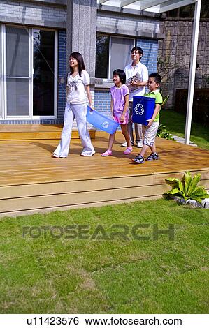 Stock Photograph - Young family with two children holding recycling bin and newspaper together. Fotosearch