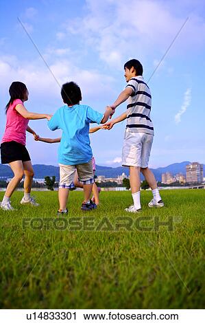 Young family with two children playing on the lawn and holding hands together View Large Photo Image Stock Image - Young family with two children playing on the lawn and holding hands together. Fotosearch