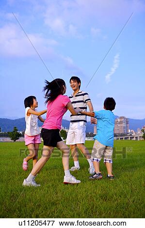 Young family with two children playing on the lawn, holding hands together and smiling happily View Large Photo Image Stock Photo - Young family with two children playing on the lawn, holding hands together and smiling happily. Fotosearch
