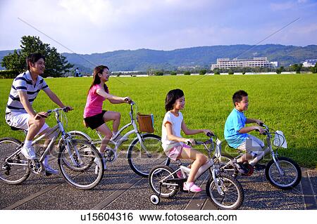 Young family with two children riding bicycles along riverbank park View Large Photo Image Stock Photograph - Young family with two children riding bicycles along riverbank park. Fotosearch