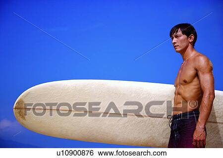 Man holding the surfboard and looking away View Large Photo Image Stock Photograph - Man holding the surfboard and looking away. Fotosearch