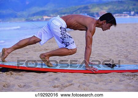 Man practicing on the surfboard on beach, side view View Large Photo Image Stock Photograph - Man practicing on the surfboard on beach, side view. Fotosearch