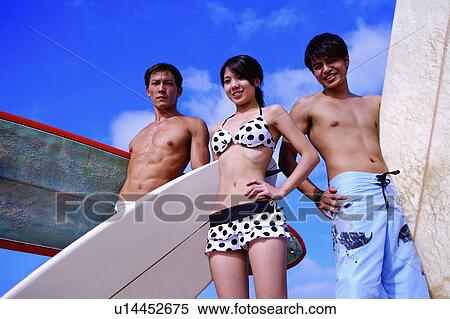 Stock Photography - Three good freinds holding surfboards and looking at the camera. Fotosearch