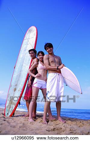 Stock Photography - Three people holding the surfboards and looking at the camera. Fotosearch