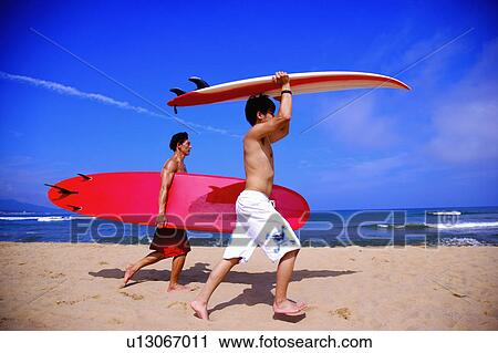 Two people holding the surfboards and walking on the beach View Large Photo Image Stock Image - Two people holding the surfboards and walking on the beach. Fotosearch