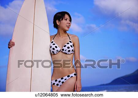 Young woman holding a surfboard and looking away View Large Photo Image Stock Photography - Young woman holding a surfboard and looking away. Fotosearch