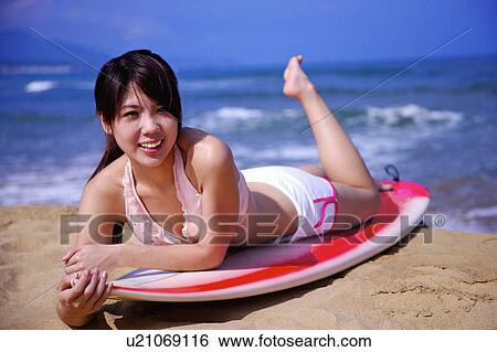 Young woman lying on the surfboard on front and looking away View Large Photo Image Stock Photograph - Young woman lying on the surfboard on front and looking away. Fotosearch