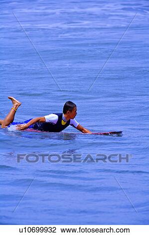 Stock Image - Man floating on the sea with the surfboard. Fotosearch
